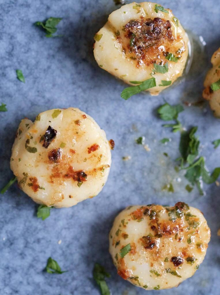 Scallops with a g​a​rli​c and fresh herb butter.