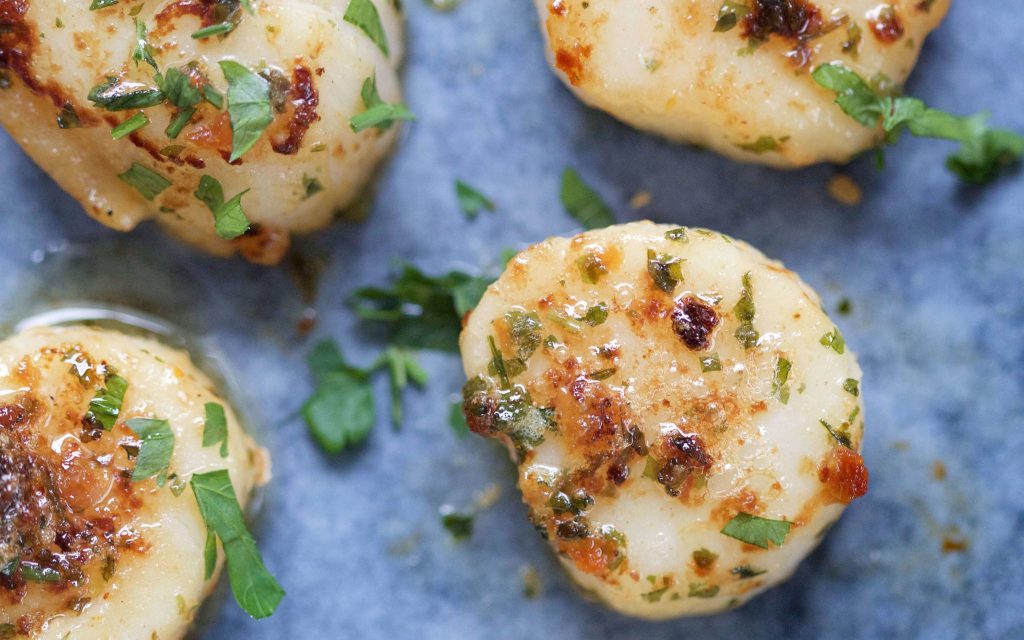 Scallops with a g​a​rli​c and fresh herb butter.