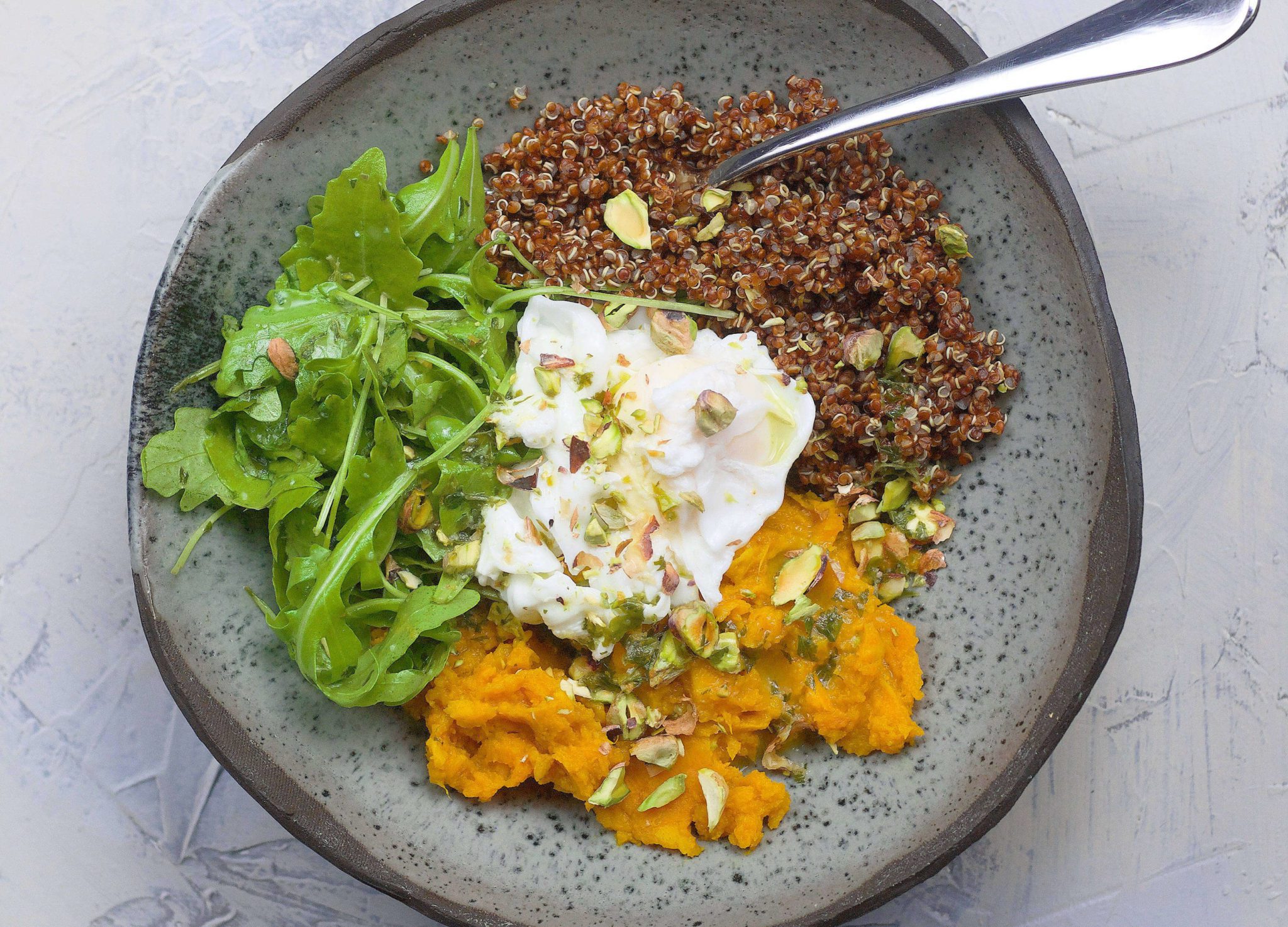 1 cup red quinoa 2 large sweet potatoes, cut into chunks 3 tbsp olive oil 1-2 teaspoons turmeric 3 cloves garlic 2 cups vegetable bullion 1/4 cup lemon juice 2 teaspoons agave syrup 1/4 cup parsley leaves salt freshly cracked black pepper 2 poached eggs handful fresh rucola crushed pistachios or other nuts for topping